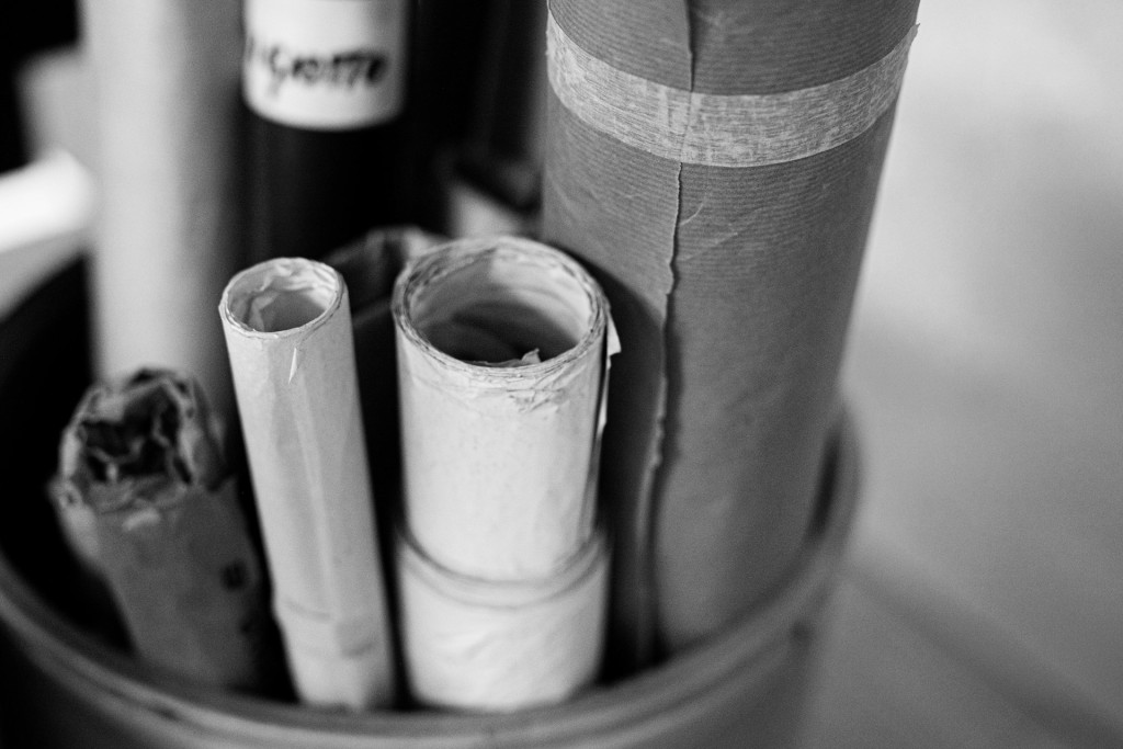 Black and white photo of several large rolls of paper inside a bucket. 